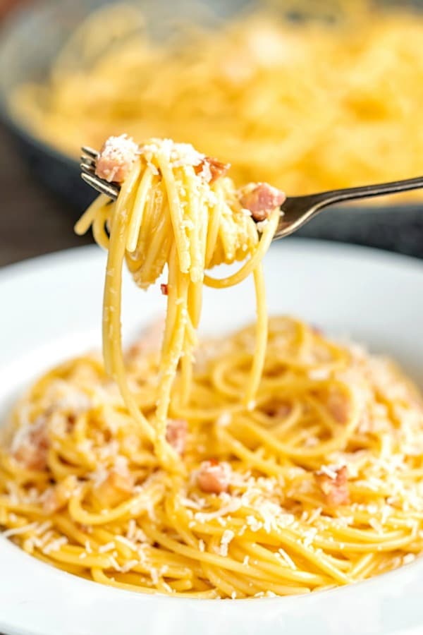 classic carbonara in a plate on a fork