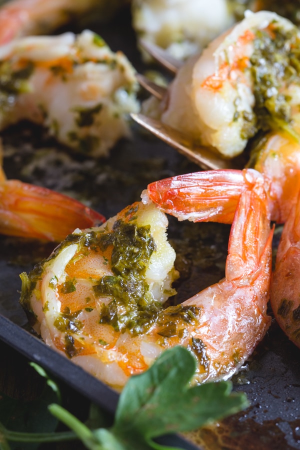 baked shrimp with a parsley sauce on a white plate