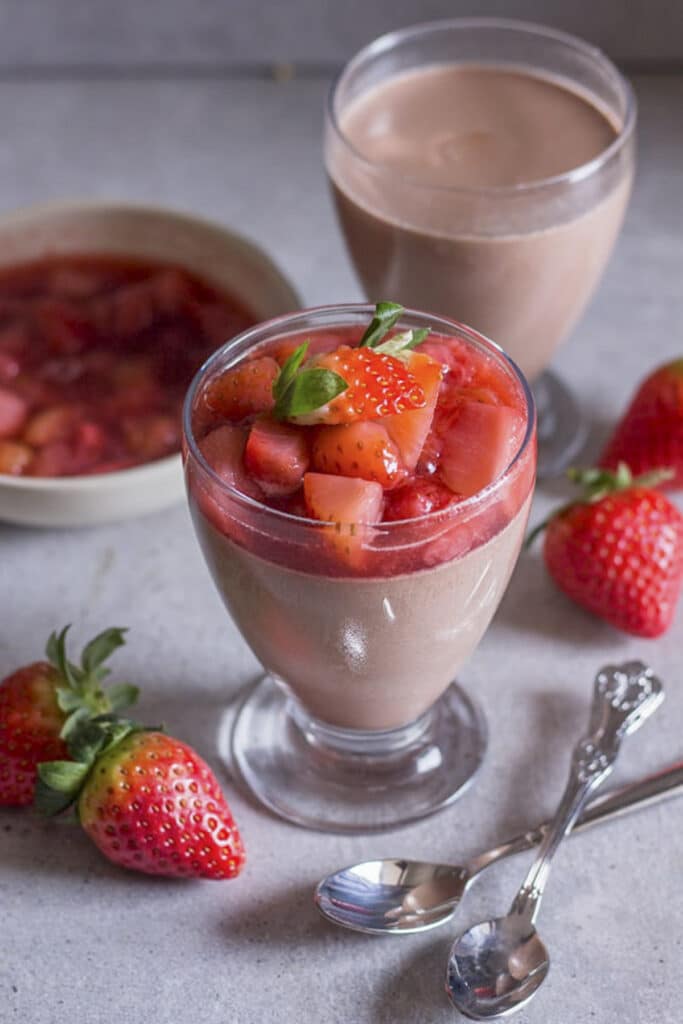 Chocolate panna cotta in a glass with a strawberry topping.