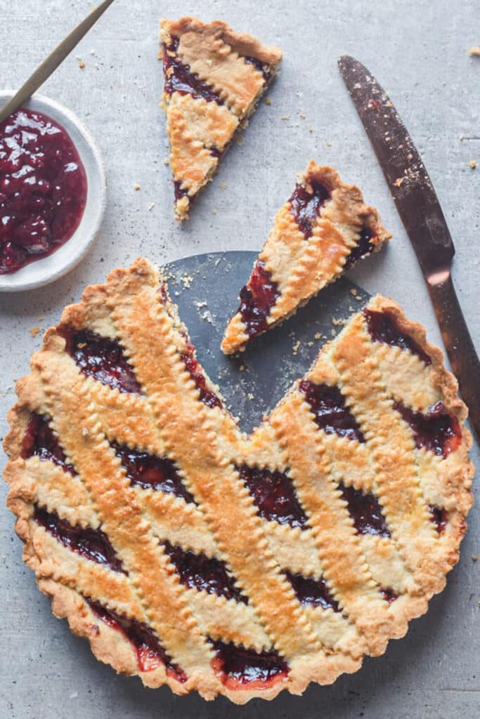 Crostata on a board with two slices cut.