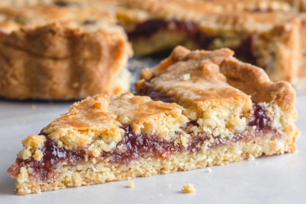 A slice of a crostata on a board.