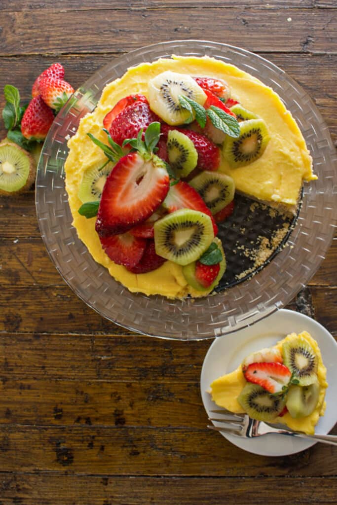 Fruit tart on a plate with a slice on a white plate.