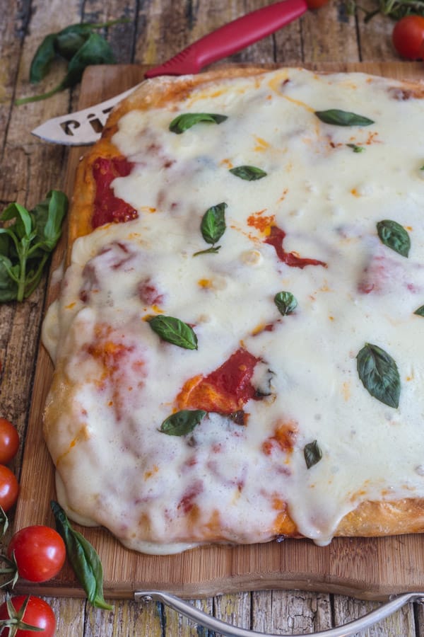 no knead pizza dough baked margherita pizza on a wooden board
