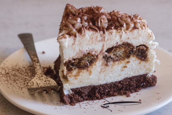 upclose tiramisu cheesecake slice on a white plate