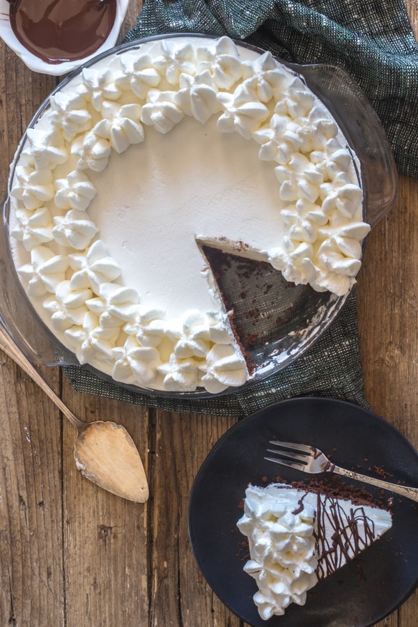 baileys mousse pie on a wooden board with a slice on a black plate