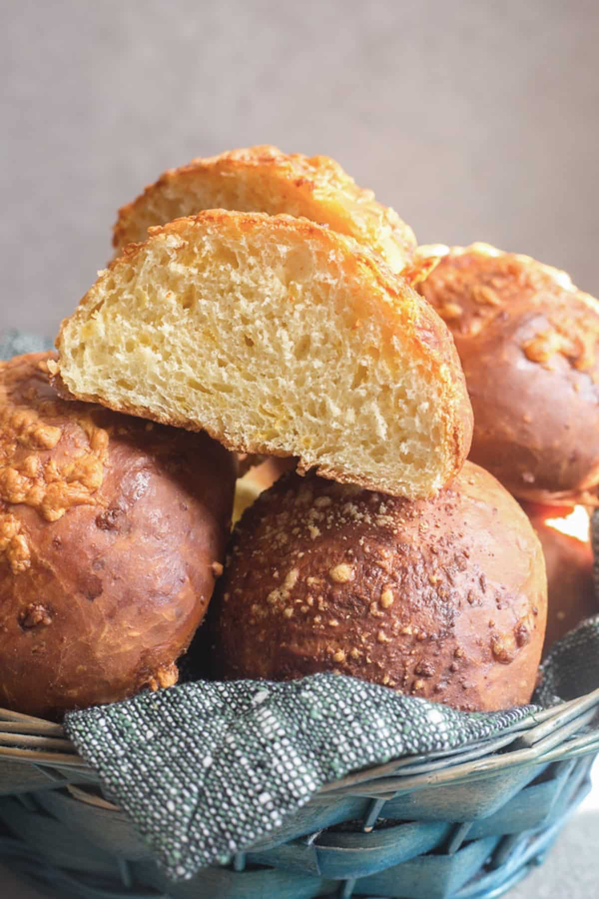 Cheese buns in a basket with one cut in half.