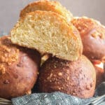 Cheese buns in a basket with one cut in half.