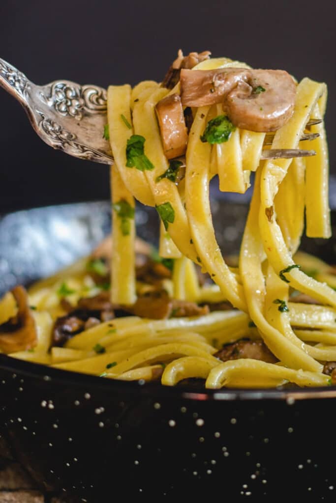 Fettuccine on a fork with some mushrooms.