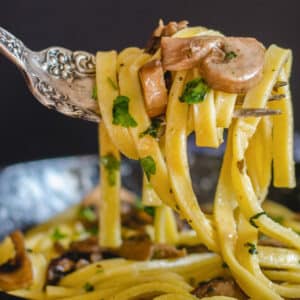 Fettuccine on a fork with some mushrooms.