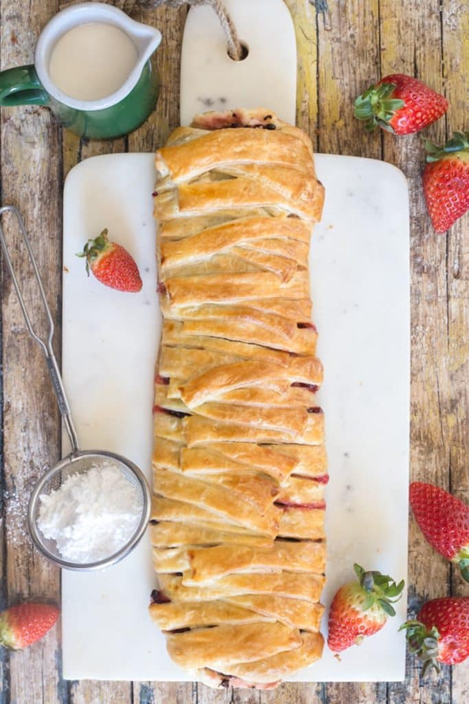 Strudel on a white board with some strawberries.