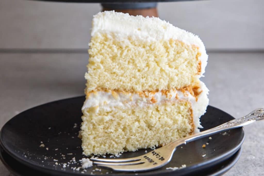 A slice of cake on a black plate.