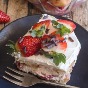 A slice of tiramisu on a black plate.