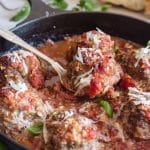 baked meatballs in a pan with one on a spoon