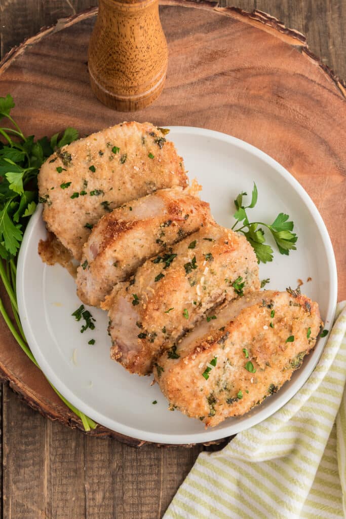 Four pork chops on a white plate.