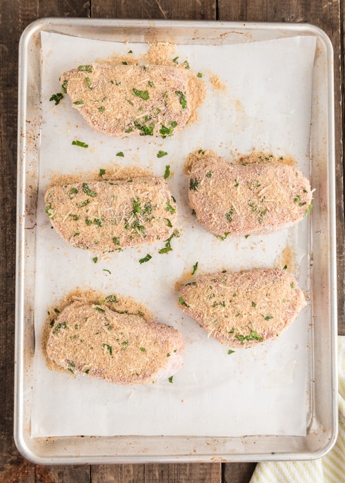 The pork chops on a baking sheet before baking.