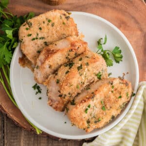 Four pork chops on a white plate.