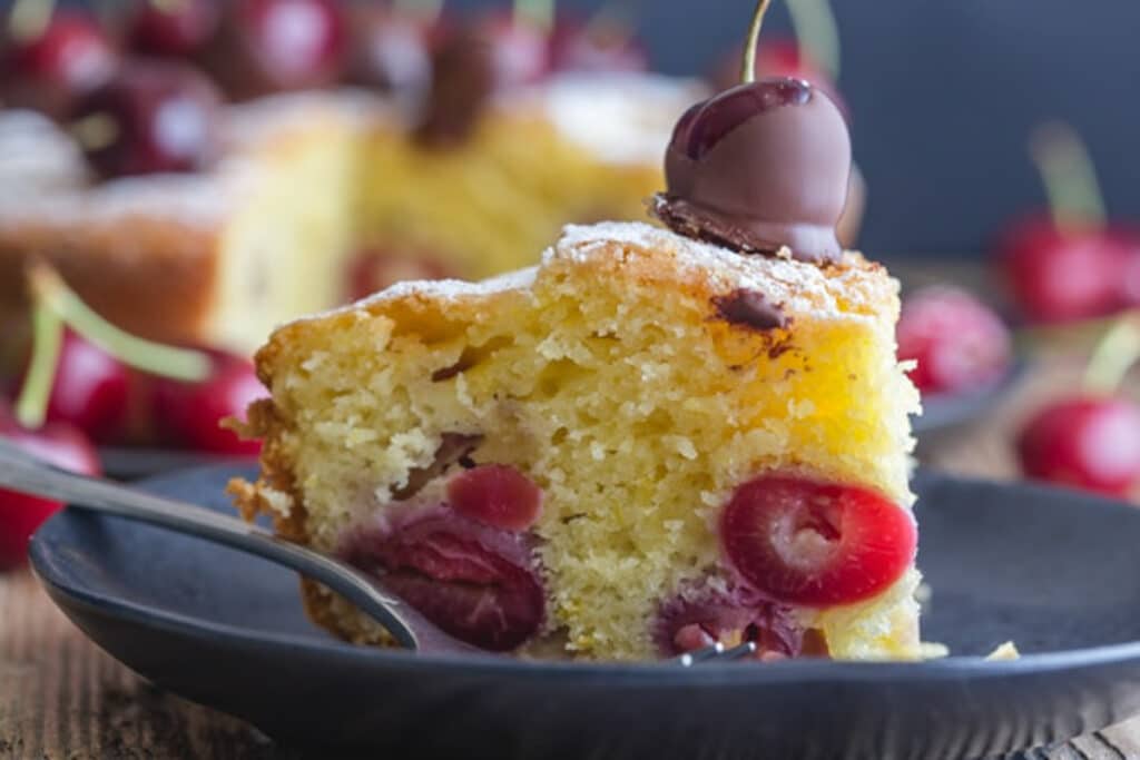 A slice of cake on a black plate.