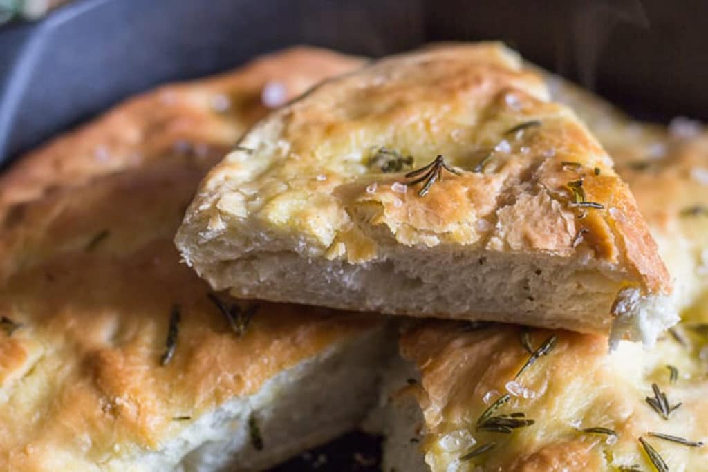 A slice of focaccia on top of the finished bread in the pan.