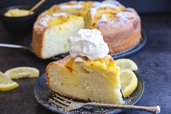 a slice of pastry cream filled lemon cake and a dollop of whipped cream on top.