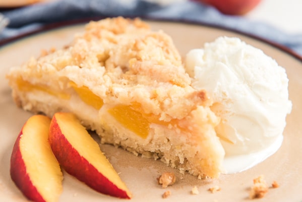 a slice of peach cake on a plate with a scoop of vanilla ice cream and 2 slices of peaches