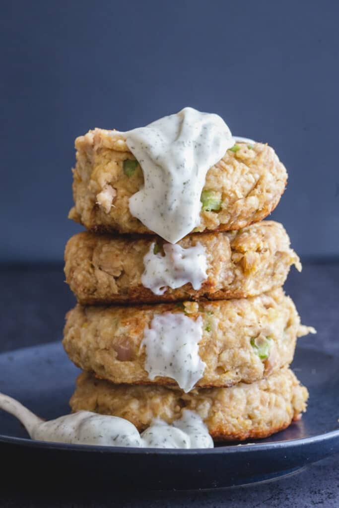 Four stacked tuna patties with dill sauce dripping down.