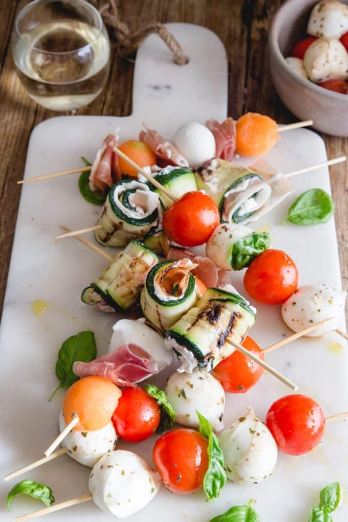 Antipasto skewers on a white board.