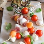 Antipasto skewers on a white board.