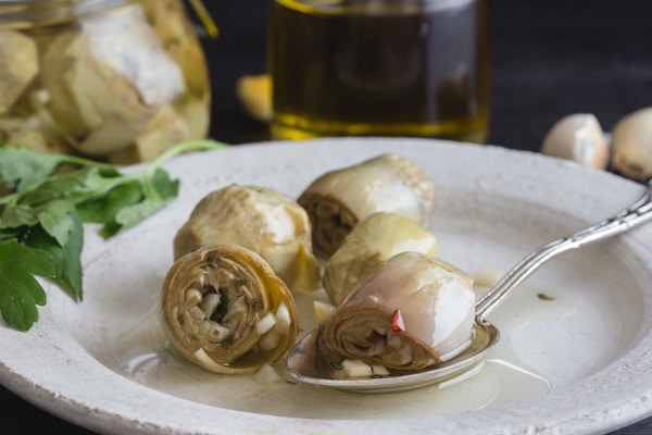 artichokes under oil on a white plate