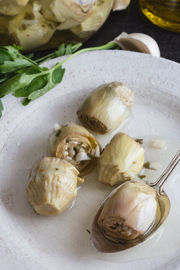 artichokes under oil on a white plate.