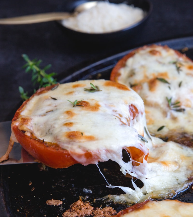 lifting a baked tomato with cheese pull