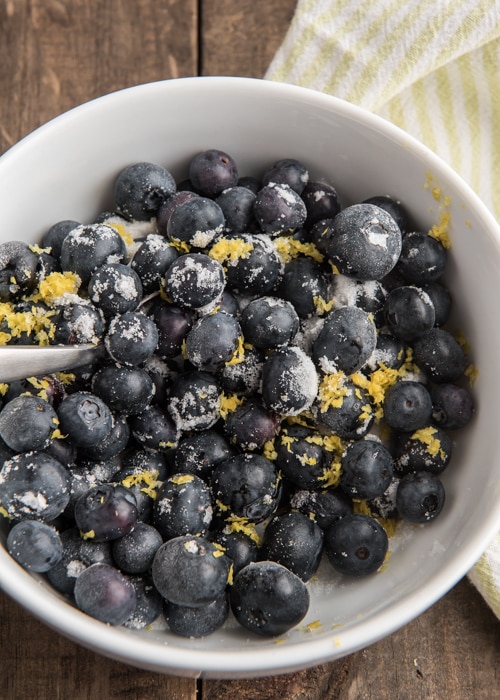 Mixing the blueberries, sugar and zest in a white bowl.