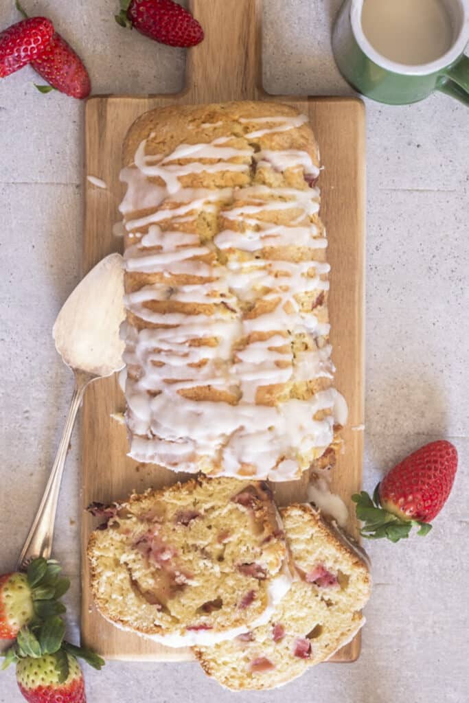 Strawberry bread on a wooden board with two slices cut.