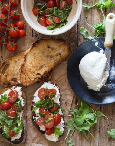 burrata bruschetta on a brown paper with fresh tomatoes