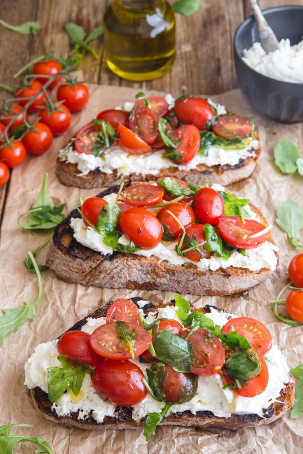 burrata bruschetta on a brown paper with fresh tomatoes