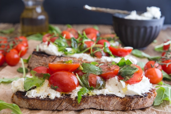 burrata bruschetta on a brown paper with fresh tomatoes