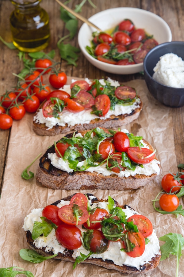 burrata bruschetta on a brown paper with fresh tomatoes