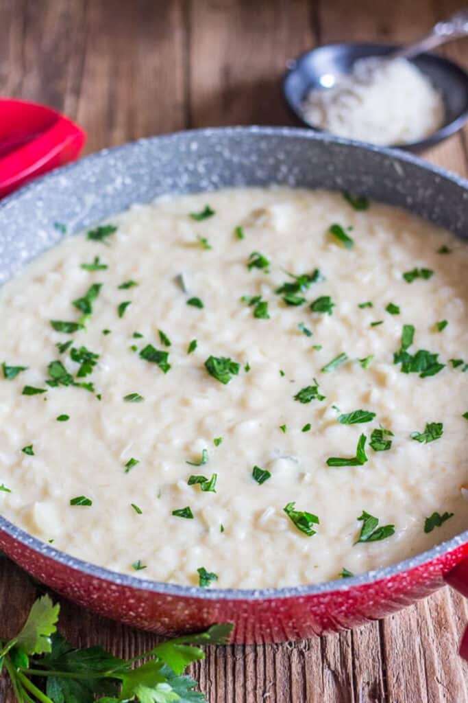 Cheese risotto in a red pan.