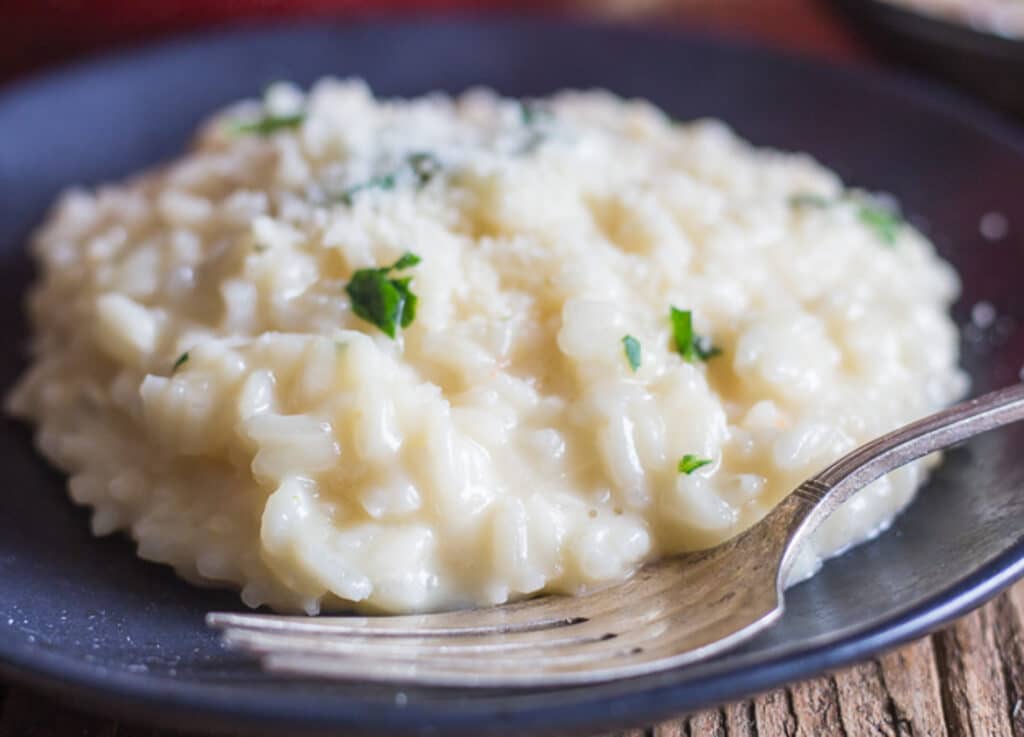 Cheese risotto on a black plate.