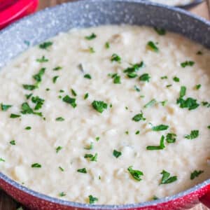 Cheese risotto in a red pan.