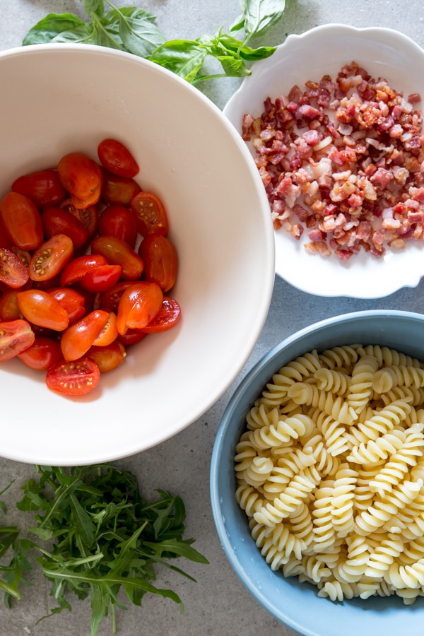 ingredients for pasta salad tomatoes, pancetta and pasta in bowls