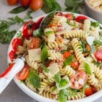 pasta salad in a bowl with tomatoes and oil on the side
