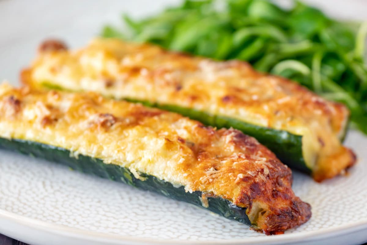 Two zucchini boats on a white plate with salad.