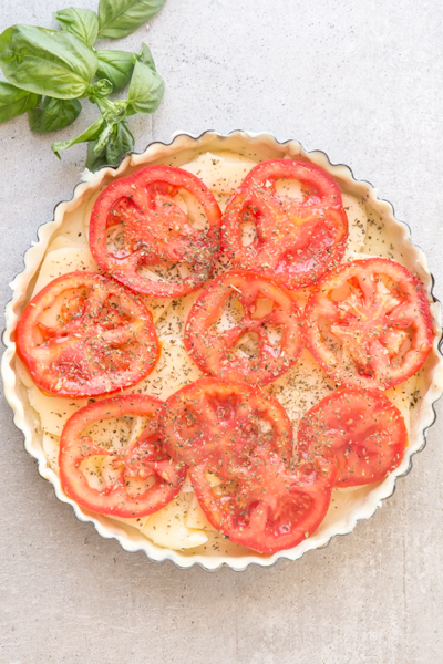 The tomato slices on top of the cheese with spices sprinkled on top.