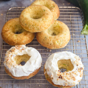 Zucchini donuts on a wire rack, two are frosted four are plain.