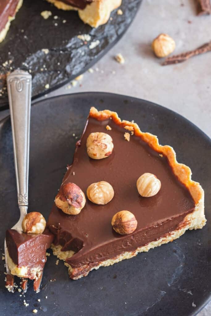 A slice of chocolate pie with a piece cut.