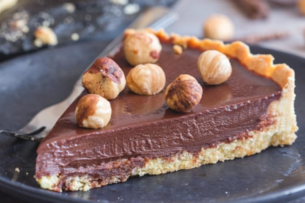 A slice of chocolate crostata on a black plate.