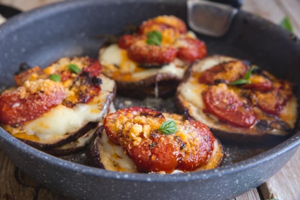 Eggplant parmesan stacks in a black pan.