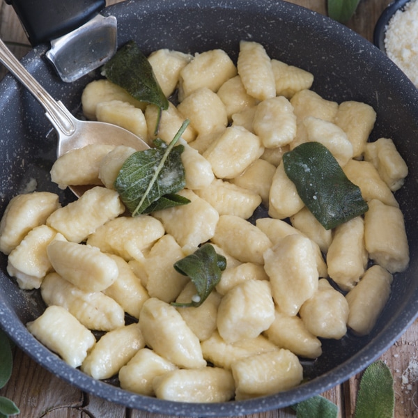 ricotta gnocchi with sage leaves in a black pan