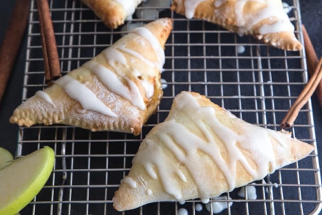 Apple turnovers on a wire rack.