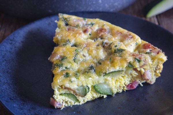 up close slice of baked frittata on a black plate